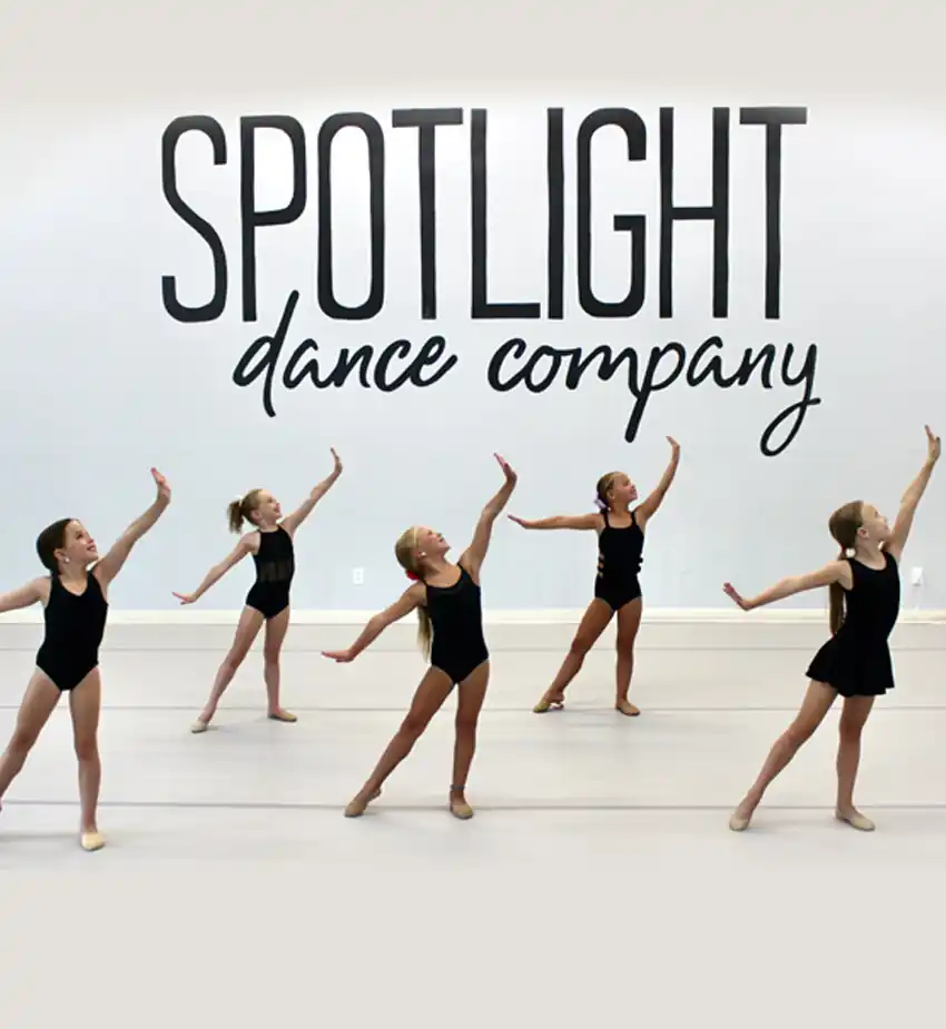 Spotlight Dance Company dancers posing beneath the studio logo