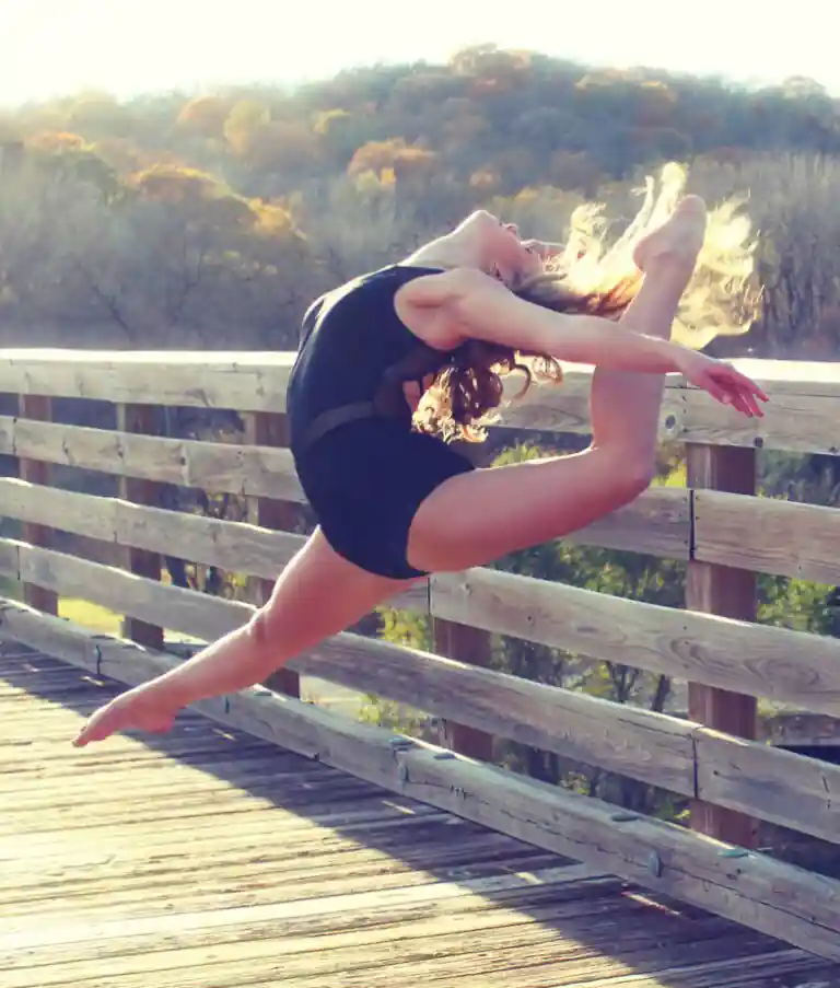 Competitive dancer performing an outdoor leap and flexibility pose