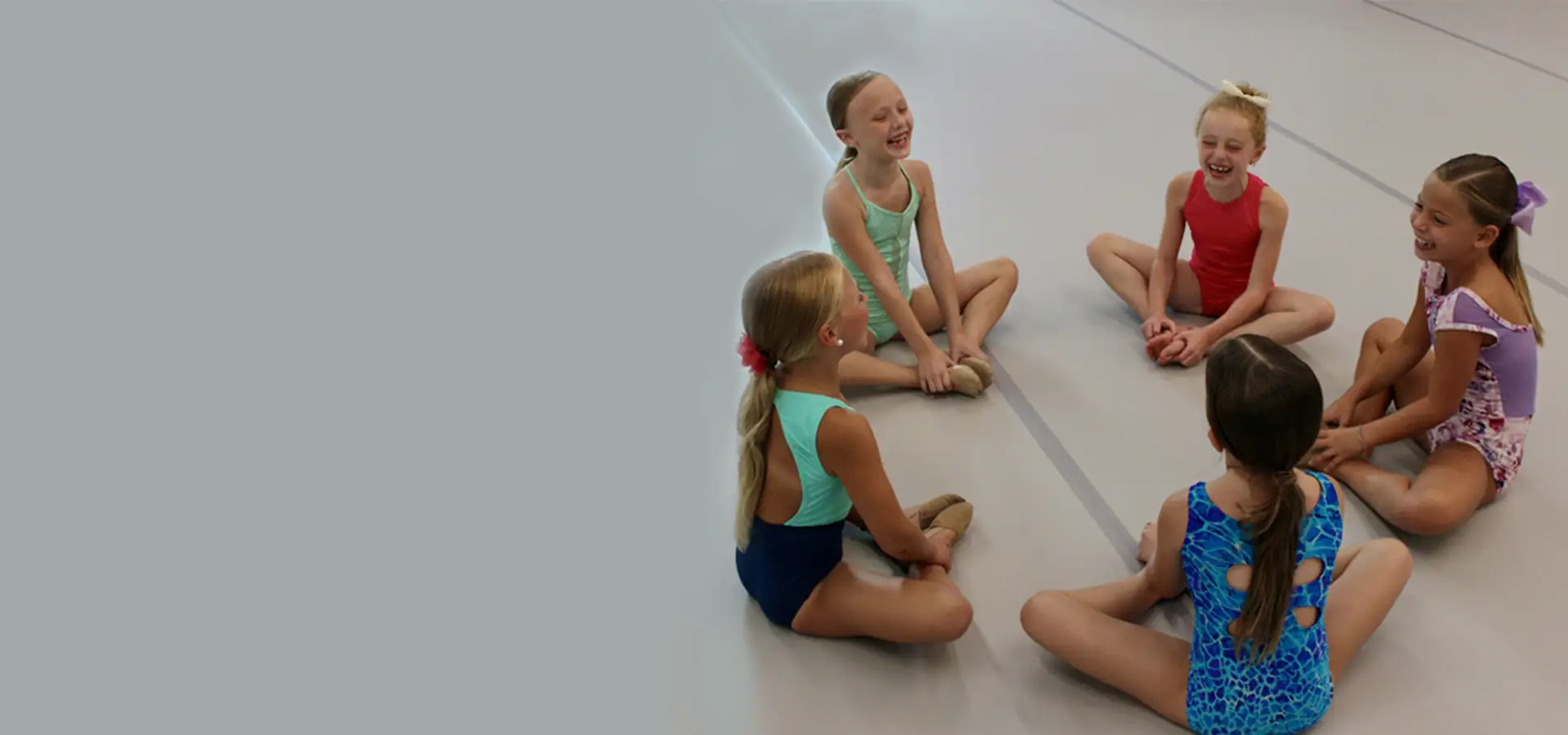 Young dancers sitting together and smiling in the Spotlight Dance Company studio